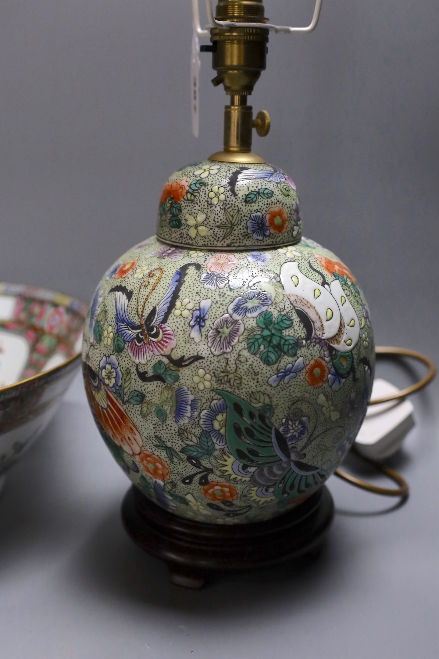 A Chinese famille verte vase converted into a lamp decorated with butterflies amongst botany, together with a famille rose punch bowl with quad-split panel decoration of floral landscapes, 31.5cm diameter